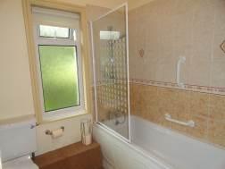 59m) having a white suite comprising a panelled bath with a shower attachment and a glazed shower screen, a pedestal wash hand basin with a tiled splash back and a WC low suite.