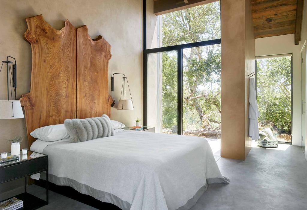 One of the guest bedrooms connects to the forested landscape via sliding glass doors topped by a large window.