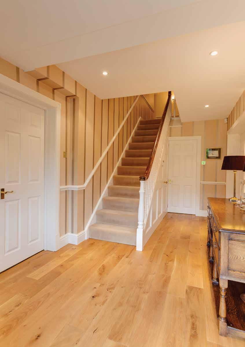 Red Croft Entrance Hall With oak flooring, recessed lighting, dado rail, central heating radiator and stairs with attractive handrail and spindles rising to the first floor with a useful under-stairs