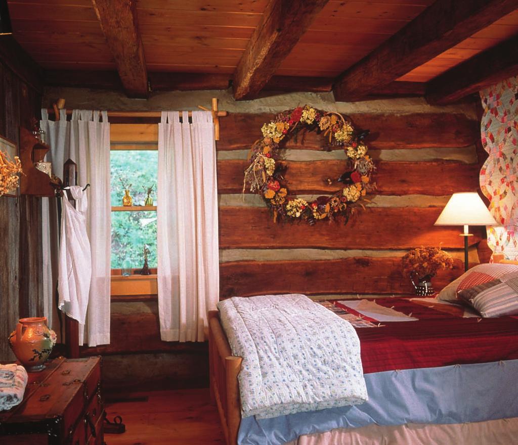 The cabin bedroom has a nostalgic flair thanks to the warmth of old wood. White pine floors complement the recycled chestnut logs.