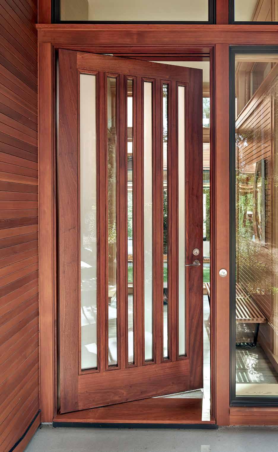 A custom entry door made of sapele wood with alternating vertical panels of etched and clear glass, from Lakeview Millworks, makes a striking first impression at the entrance to a Bend home designed