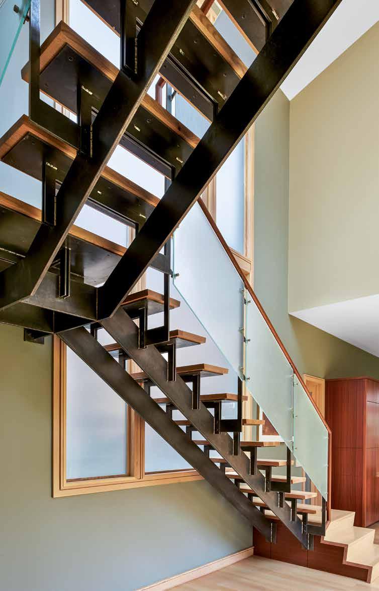 Above: The home s open stairway made of exposed steel with glass railing panels and floating wood treads serves as an architectural link between the