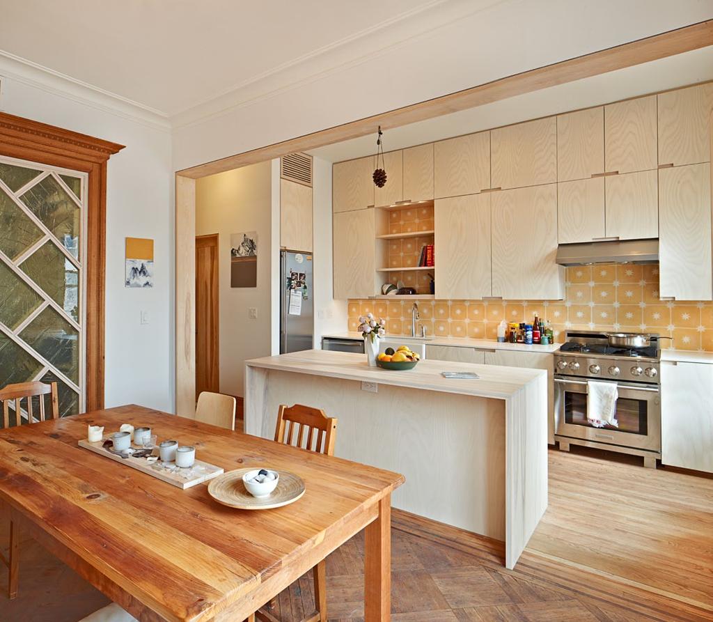 The open kitchen and dining area features new cabinetry, appliances and handmade tiles with restored woodwork