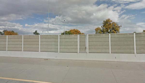 A concrete safety barrier separates eastbound from westbound traffic along this six-lane segment.