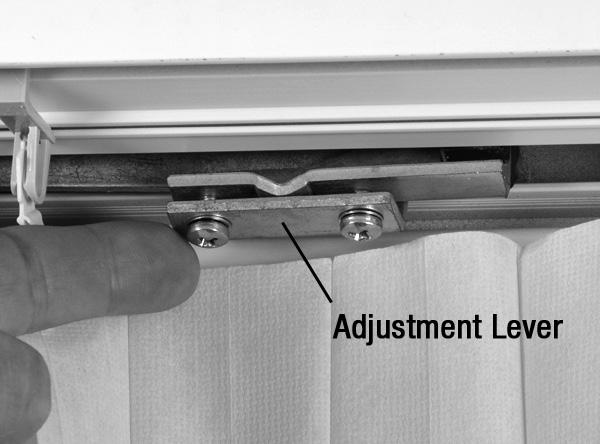 To access the lever, carefully push back the top of the fabric on the moving rail side
