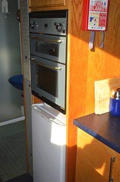 Full height oven & fridge housing with cupboard above.