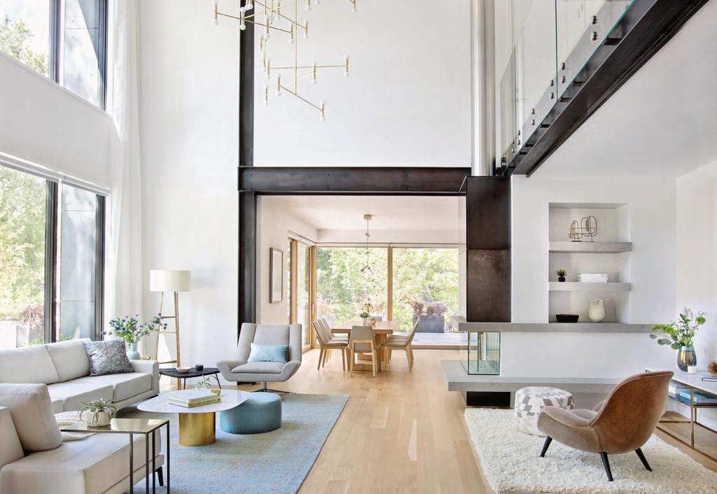 In the double-height living room, a burnished-brass chandelier by Lambert & Fils hangs above whiteoak floors.