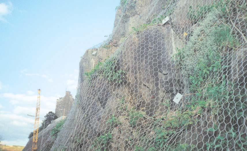 The PVC-coated double-twist wire mesh is typically fixed to a stable rock slope using mechanical or resin anchors.
