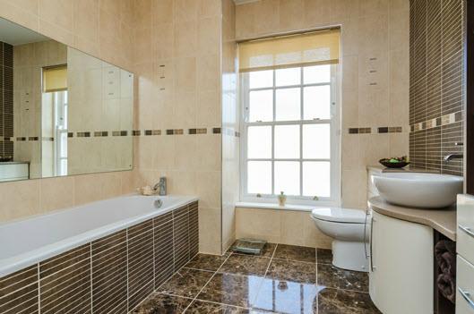 low flush wc, vanity unit, panelled shower cubicle, fully tiled walls with mosaic design,
