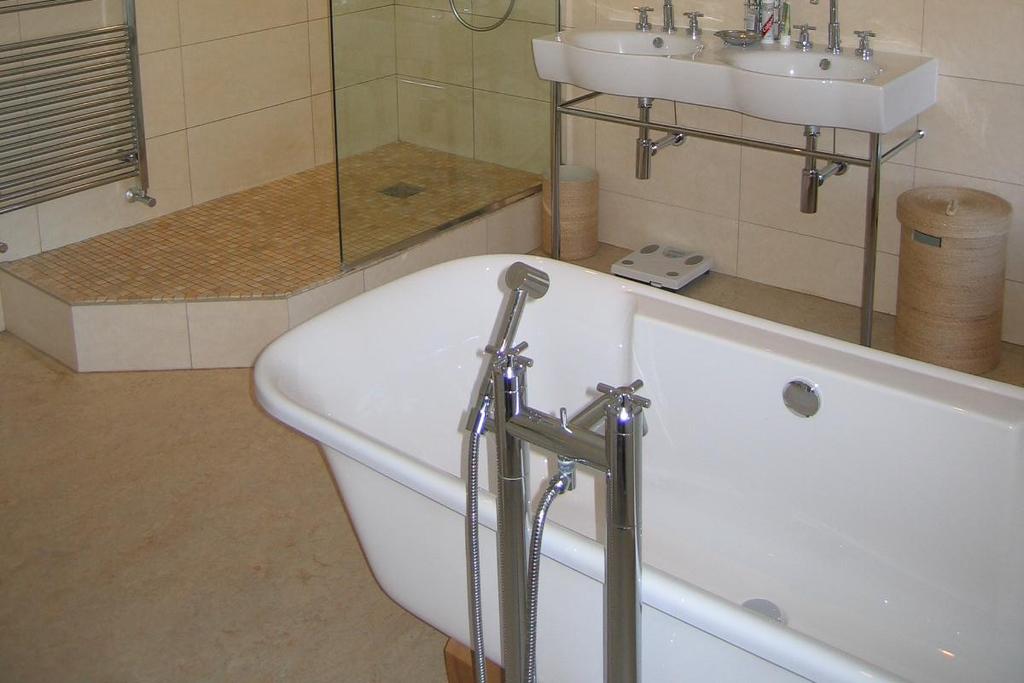 SHOWER ROOM/WC refurbished with contemporary white suite with modern chrome fittings comprising Low level Kohler wc, vanity unit with inset wash hand basin with tiled splashbacks, vanity shelf and