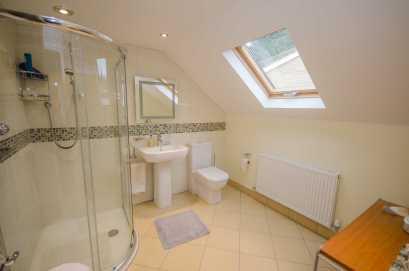 spotlights, extractor, chrome ladder style towel radiator, single radiator with thermostat, double glazed Velux roof light and tiled floor with electric underfloor