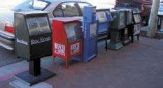 Newspaper racks should be consolidated into a single unit to reduce visual clutter.