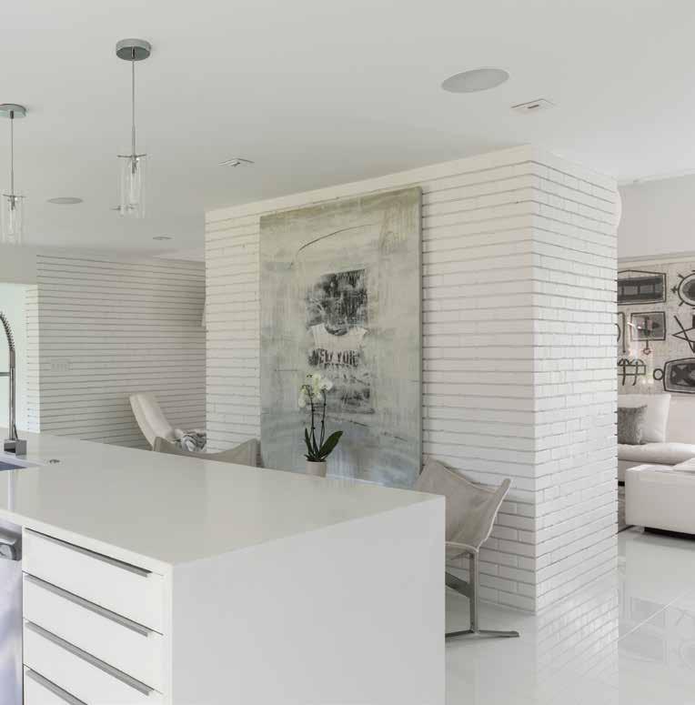 Left: The sleek kitchen is the hub of the home. White glass flooring is used throughout the entire 3,300-square-foot house. The counter stools are by Mitchell Gold and Bob Williams.