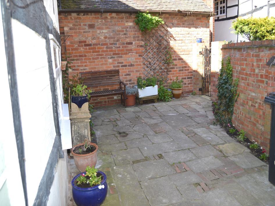 Outside the property from the kitchen/dining room there is a rear access door to the courtyard garden, paved stone with flower border, pedestrian access through wrought iron gate to access passageway