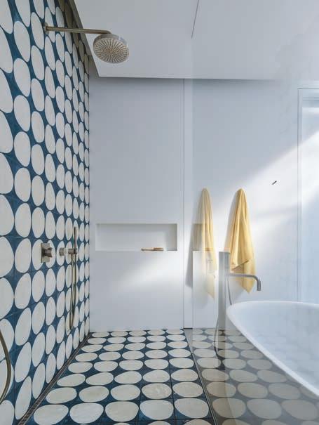 The rear wall is wrapped in an Elitis silk from Donghia, and the matching brass pendants with custom stems are from Miami-based StudioPGRB. Master bath tile is Stone by Claesson Koivisto Rune.