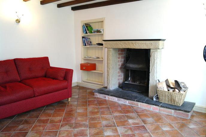Main feature of the room being a stone-built open fireplace with slate tiled hearth and slate mantle. Single panelled central heating radiator, and built-in shelving unit.