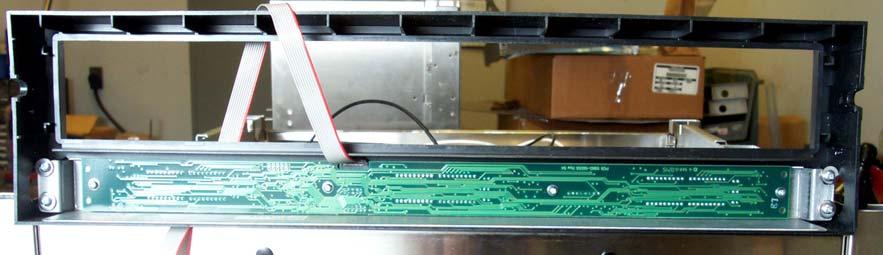 The bezel is shown removed (Figure 9). Four screws secure the display in the bezel. The ribbon cable attaches to the distribution board on the side of the unit. 2.