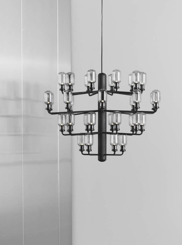 AMP CHANDELIER The show-stopping Amp chandelier is built up around a central steel cylinder, from which small arms grow out to form a voluminous oval shape.
