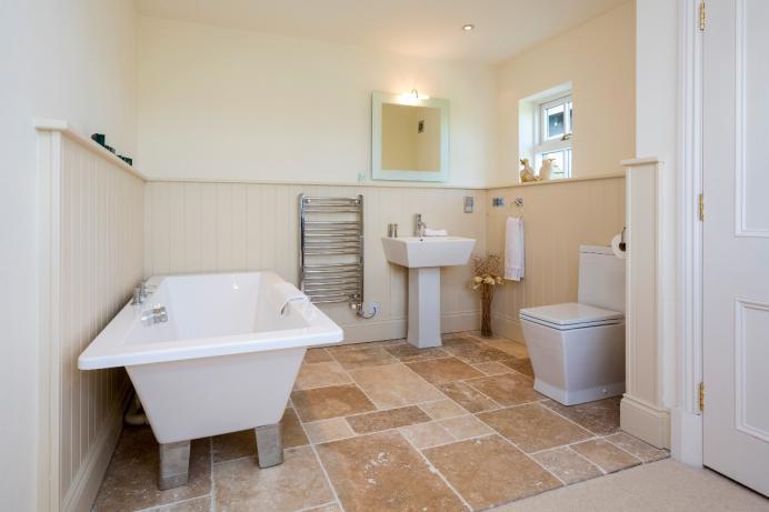 FAMILY BATHROOM Window to front elevation, contemporary white suite comprising of low flush WC, panelled bath, wall mounted wash hand basin, heated towel rail, floor and part wall tiling, ceiling