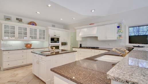 Custom white display and storage cabinetry with crown molding provide plenty of above and below counter storage and are highlighted by ontrend granite countertops and color