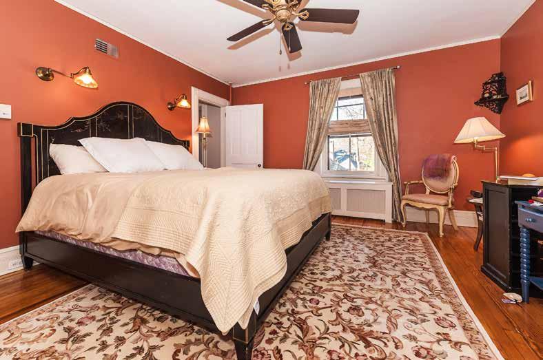 Master Bedroom with original wide-plank hardwood floor, antique ceiling fan with light, 2 windows with custom window treatments,