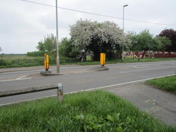 Realign road junction and replace bus layby with bus stop in carriageway and use space for a widened path.