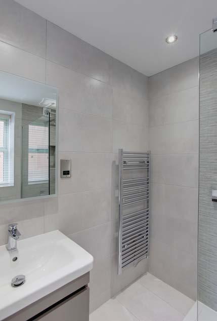 Duravit bath with tiled side panel and a wall mounted rain head shower and glazed screen.