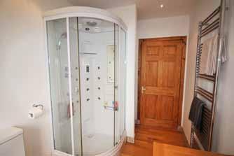 Chrome heated towel rail, spot lights to the ceiling, wood flooring, extractor fan and an obscure upvc double glazed window