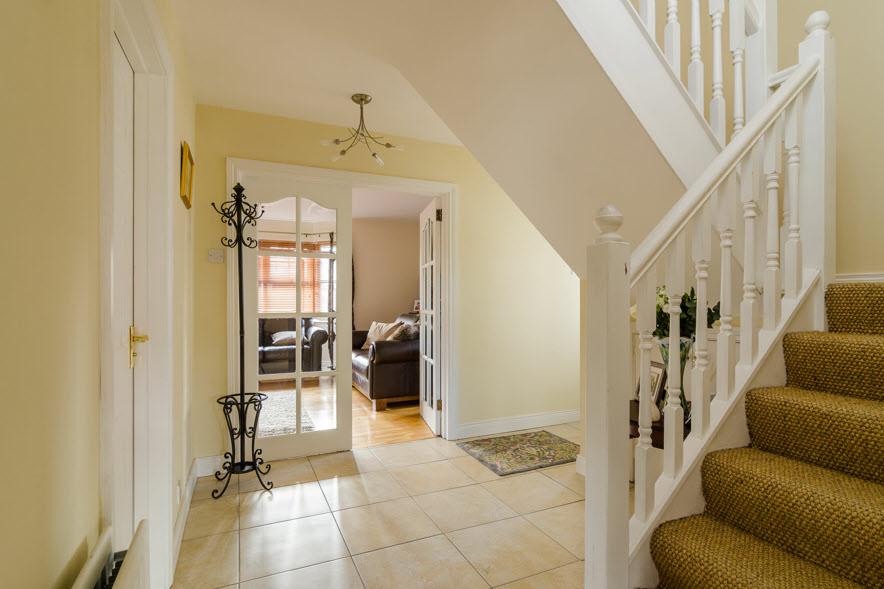 ENTRANCE HALL: Ceramic tiled floor, solid wood panelled door to front, storage under stairs.