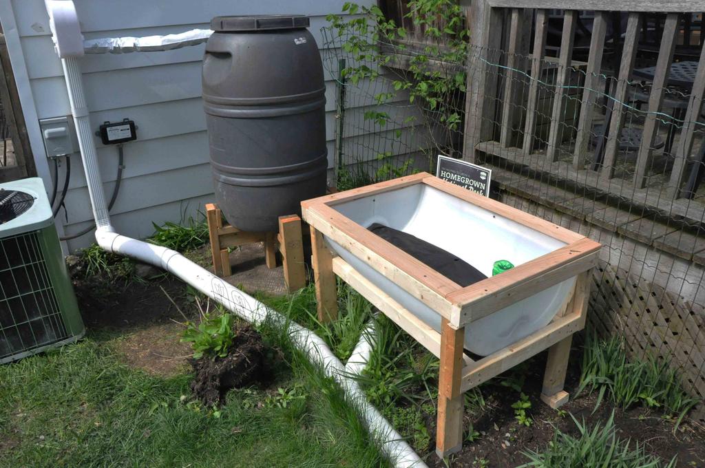 Raised Sub-irrigated Planter and the Rain-barrel are connected via a regular plastic water hose for ease