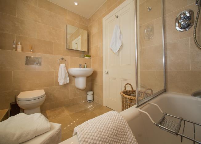 First floor landing A smart contemporary bathroom with marble effect tiled walls, window returns and sills and a white suite with a contemporary floating low level w.c. and wash hand basin, a concealed cistern and a pressed steel bath with mixer tap, a built in thermostatic shower and a glazed shower screen.