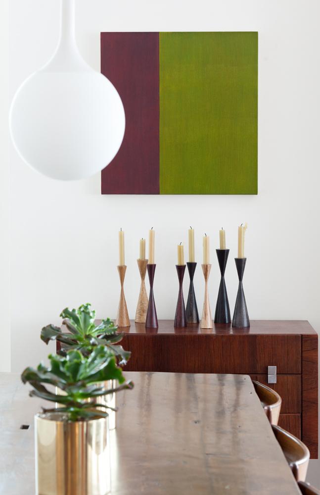 A Marcia Hafif color field painting hangs above a collection of candleholders by craftsman Edgar