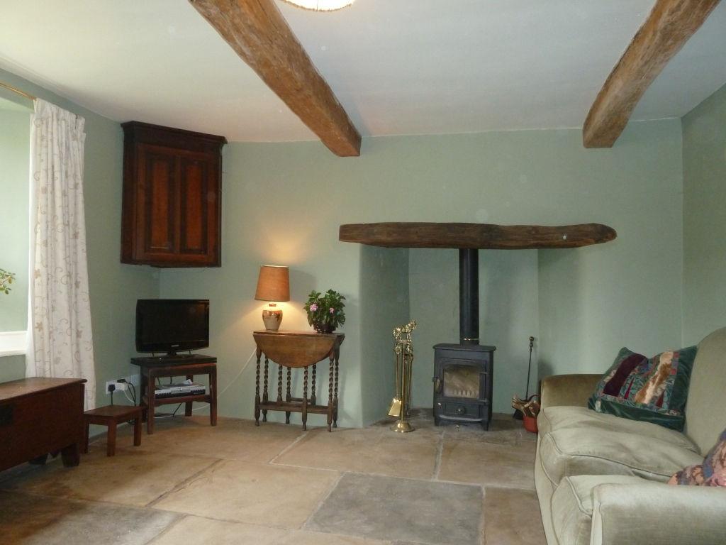 Large rectangular stone fireplace with a carved lintel surrounding a Yorkshire cast iron range. Beamed ceiling. Old wash boiler. Built-in cupboard. Pot sink.