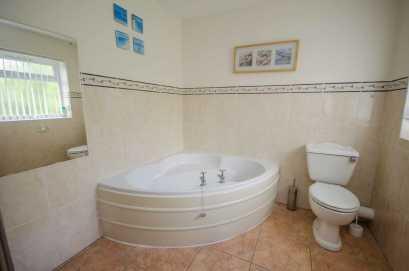 31m (14'3" maximum x 7'11" narrowing to 7'7") A large bathroom comprising: off-set corner bath; low level WC; pedestal wash hand basin; and tiled shower enclosure with triton