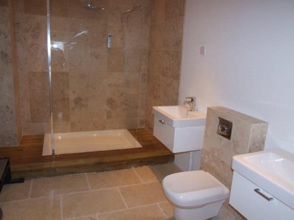 Full length upright panelled radiators with individual thermostatic controls. Modern suite with square wall mounted hand washbasins with mixer taps.