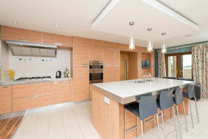 pull out larder unit; polished quartz worktops; integrated 'Smeg' stainless steel double electric eye level ovens and matching 5 ring gas hob with 'Airome' extractor unit