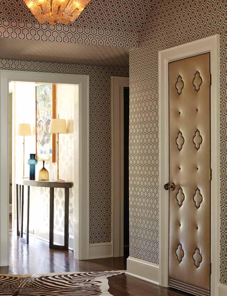 A custom upholstered door leads to the powder room, where Hicks Hexagon wallpaper by Cole & Son dots