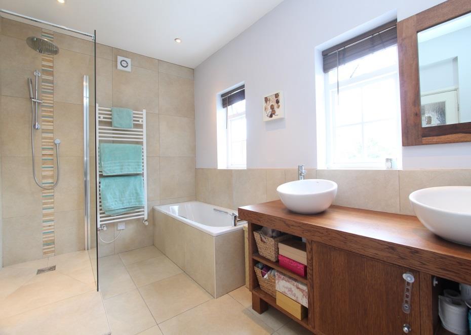 cubicle with static screen, Drench and hand held shower heads, his n hers basins set on wooden countertop with shelves and cupboards below, wc with concealed