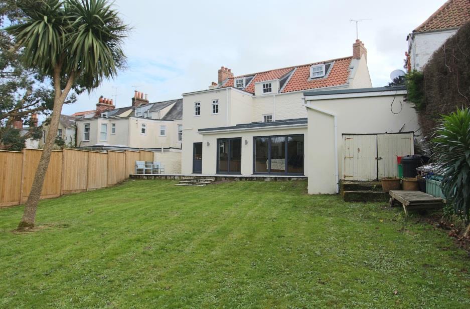 The large rear mature garden has a paved seating area directly behind the