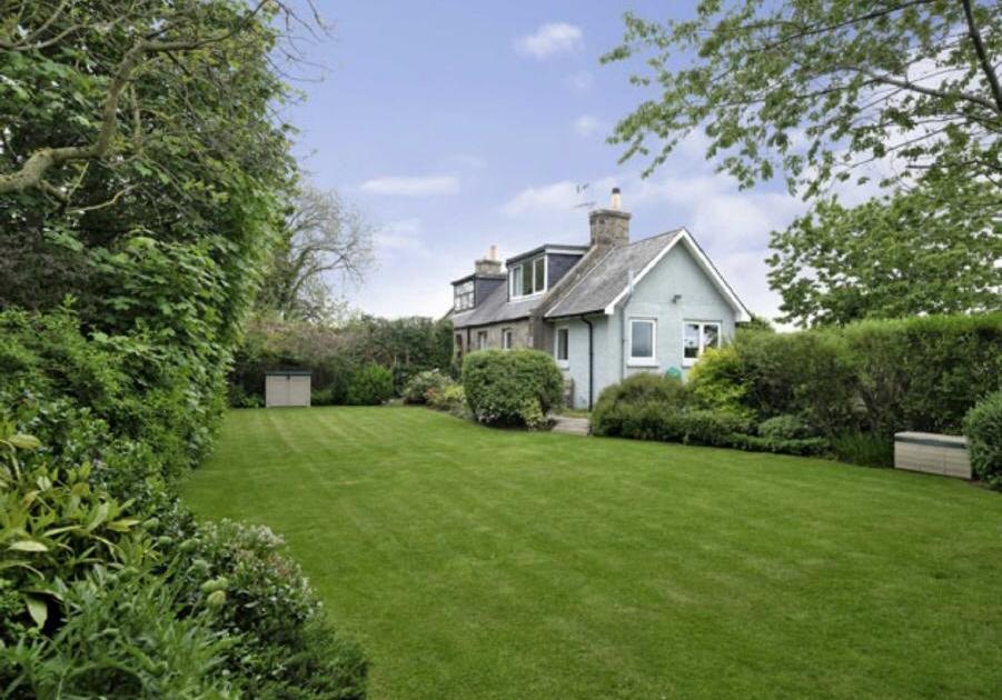 The garden to the front of the property is beautifully maintained, with a large lawn area and