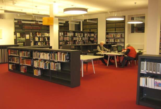 The furniture is all in nuances of grey, white, green, red and orange. Most bookcases are low and placed in dead straight rows, with one slanted shelf used to promote materials.