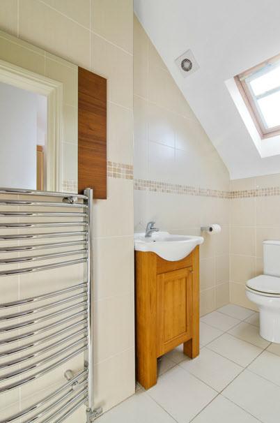ENSUITE SHOWER ROOM: White suite comprising low flush wc, vanity units, fully tiled shower cubicle, chrome heated towel rail,
