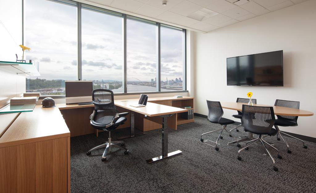 Executive offices include wall-mounted monitors and full meeting tables to gather employees and discuss topics in private.