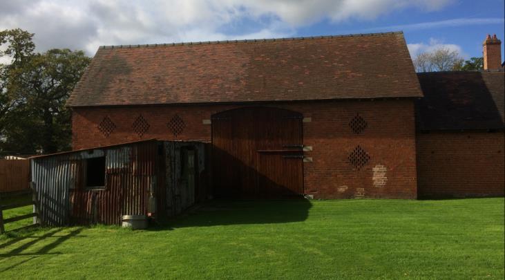 retains its cobbled threshing floor, with a rammed earth floor to its north and concrete to the south. Brick piers extend a short distance into the space to either side of the threshing floor.