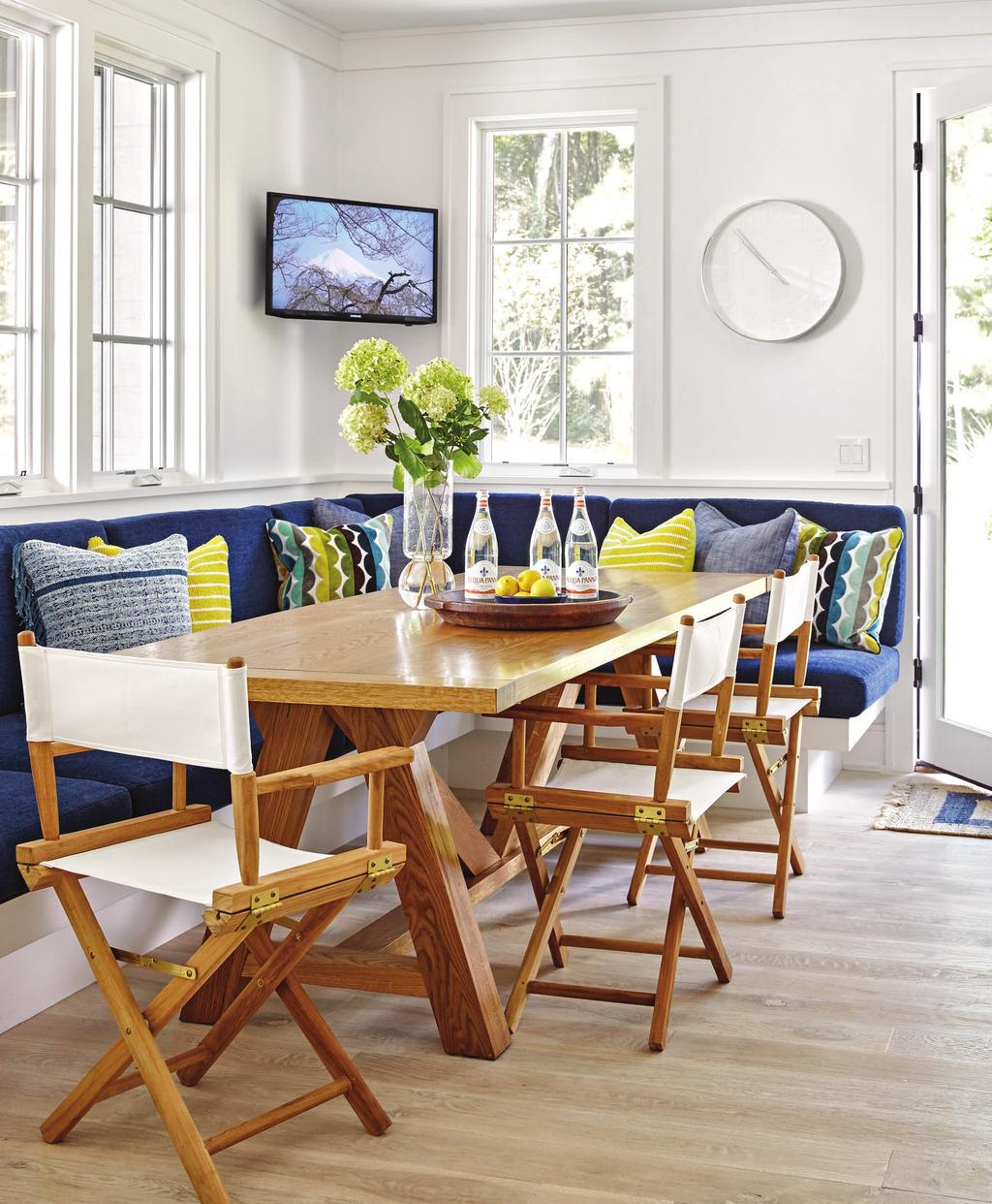 The banquette cushions wear soft but durable chenille; pillows in outdoor fabrics punch up the navy with citrusy hues.
