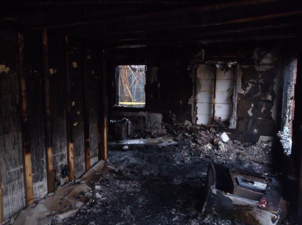 The shelving unit was heavily charred on the side facing the kitchen. The wood floor was heavily charred throughout the kitchen.
