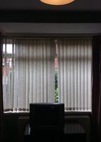 There are three sets of cream vertical blinds and brown