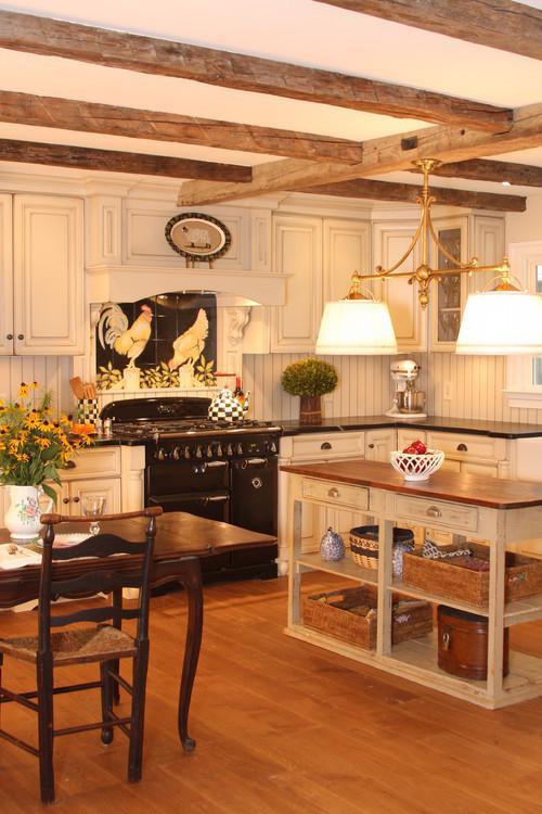The aged pale tones of cream cabinetry and contrasting dark countertop create a rich,
