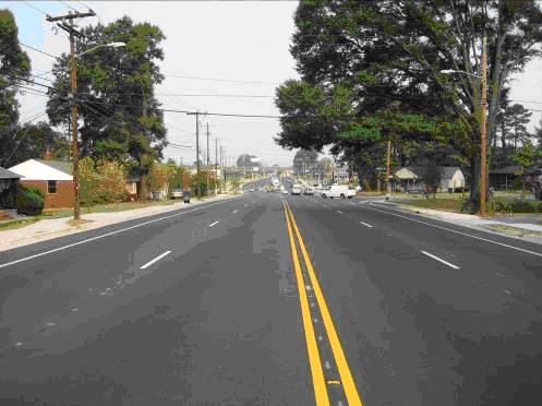 ) Woodlawn Road is generally four travel lanes wide with turn lanes added at its signalized   behind the curb and gutter.