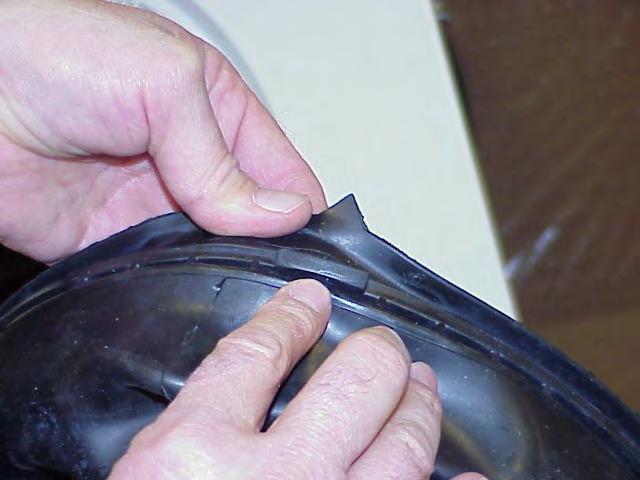 As the boot is pulled free from the outer lip of the tub (at the top), the coiled spring that holds the boot from the groove behind the lip around the opening to the front shell will become visible.